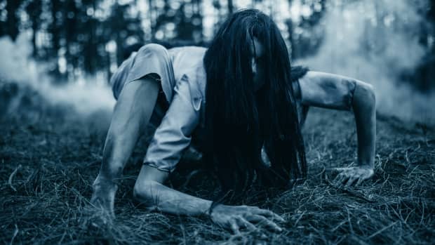 Cosplayer女孩从乌克兰在萨马拉的形象从恐怖电影《午夜凶铃》爬在地面在黑暗森林。